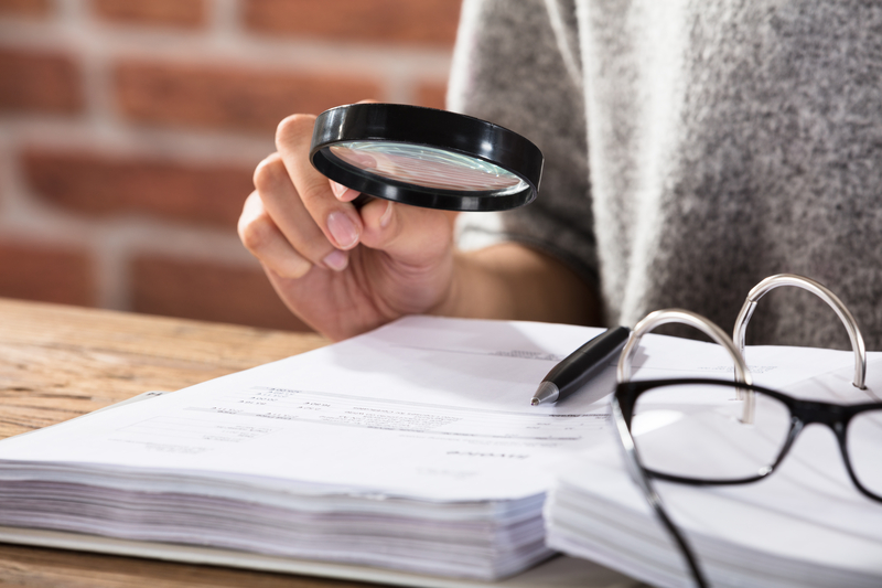 Businesswoman examining a document with a magnifying glass