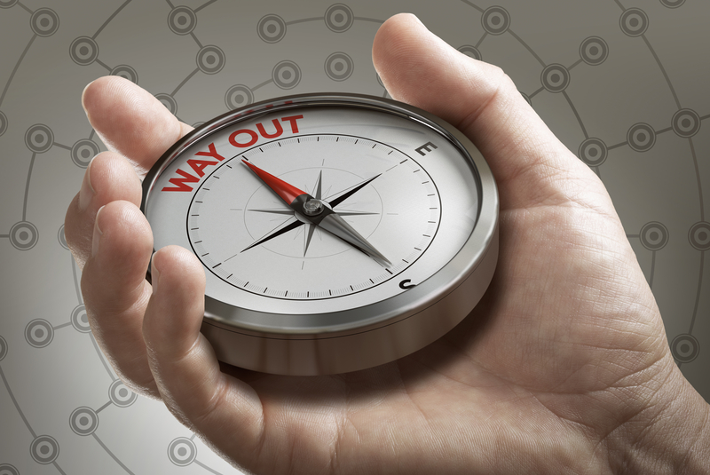 Man hand showing compass with needle pointing the text way out