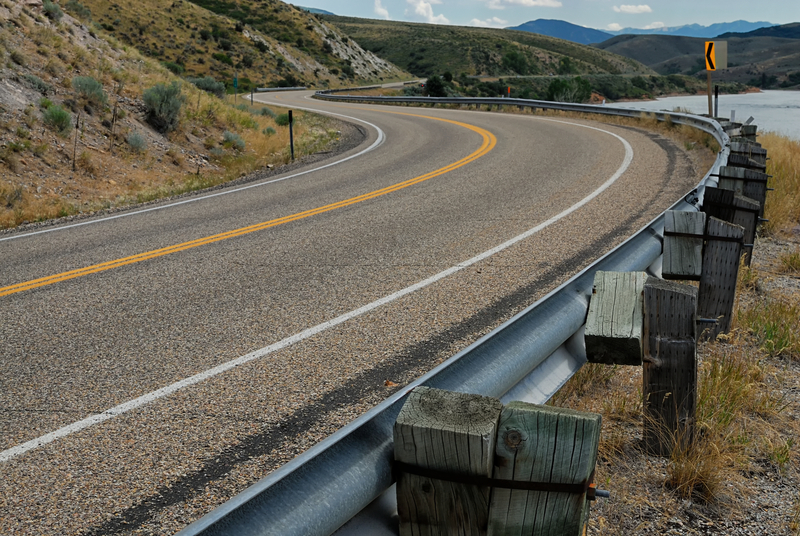 A winding highway road with guardrails in the Rocky Mountains