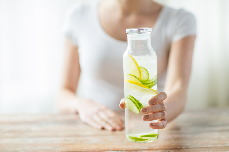 A woman reaching for a bottle of lemon water